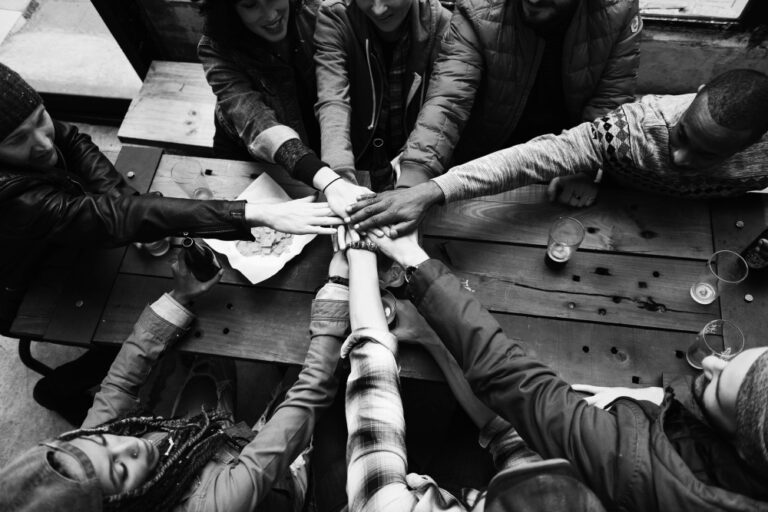 Phot d'une équipe joignant leurs mains au centre d'une table dans un geste d’unité