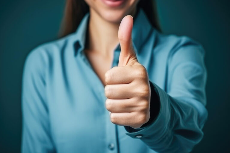 Photo d'illustration d'une femme faisant un geste de pouce levé et souriant légèrement, reflétant un ton positif et encourageant.